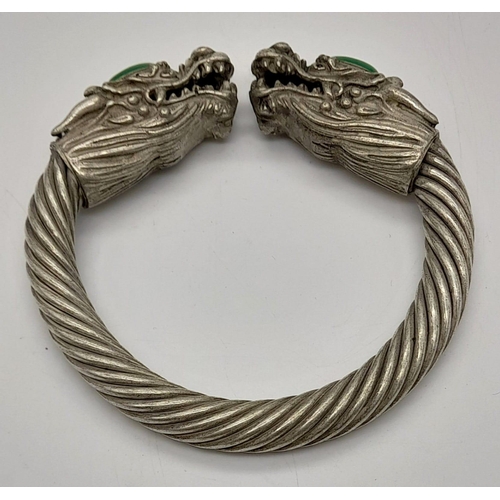 777 - A Tibetan Silver Twin Dragon Twisted Bangle/Bracelet with Green Jade head decoration. 7cm inner diam... 