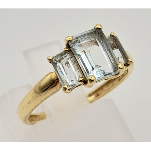 502 - A 9K Yellow Gold Emerald-Cut Three Stone Aquamarine Ring. 
Size L. 1.65g total weight.