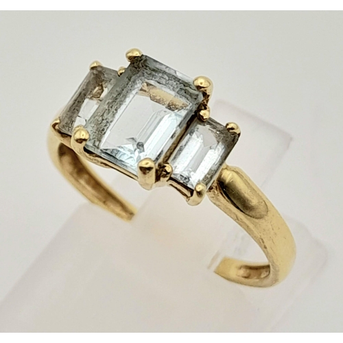 502 - A 9K Yellow Gold Emerald-Cut Three Stone Aquamarine Ring. 
Size L. 1.65g total weight.