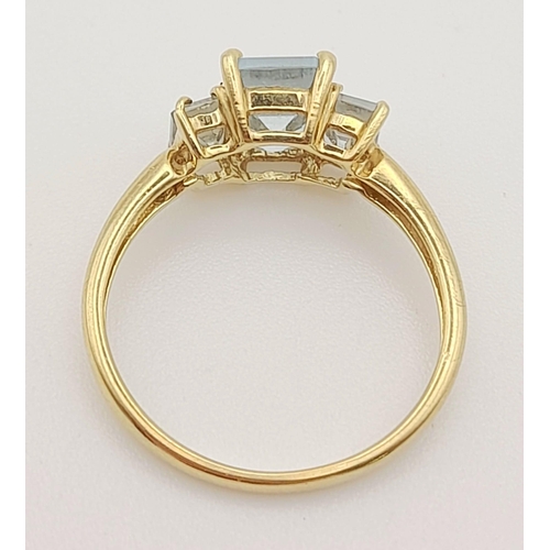 502 - A 9K Yellow Gold Emerald-Cut Three Stone Aquamarine Ring. 
Size L. 1.65g total weight.