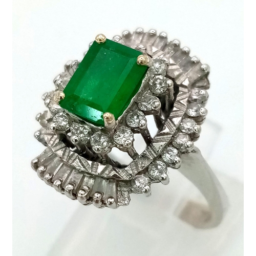 999 - An 18K White Gold Emerald and Diamond Dress Ring. Baguette cut central emerald surrounded with two l... 