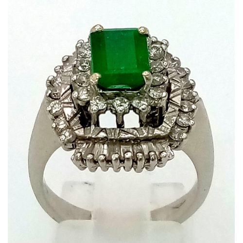 999 - An 18K White Gold Emerald and Diamond Dress Ring. Baguette cut central emerald surrounded with two l... 