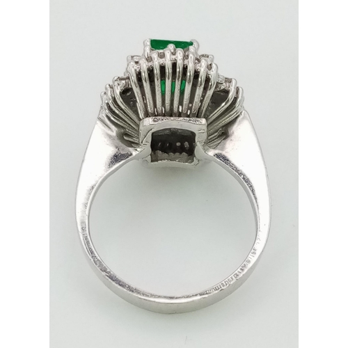 999 - An 18K White Gold Emerald and Diamond Dress Ring. Baguette cut central emerald surrounded with two l... 