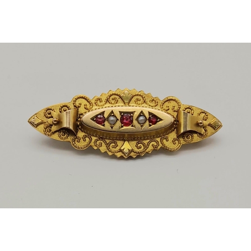 1185 - A Victorian 9K Yellow Gold Ruby and Seed Pearl Brooch. Scroll decoration. 4.5cm. 3.12g total weight