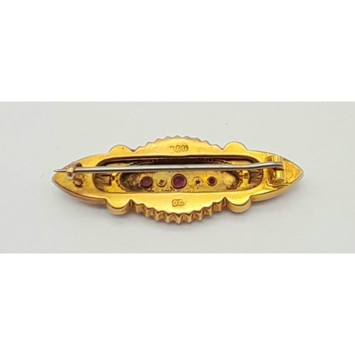 1185 - A Victorian 9K Yellow Gold Ruby and Seed Pearl Brooch. Scroll decoration. 4.5cm. 3.12g total weight