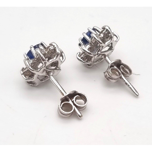 1299 - A Pair of 18K White Gold Sapphire and Diamond Stud Earrings. Oval cut sapphire with 8 round cut diam... 