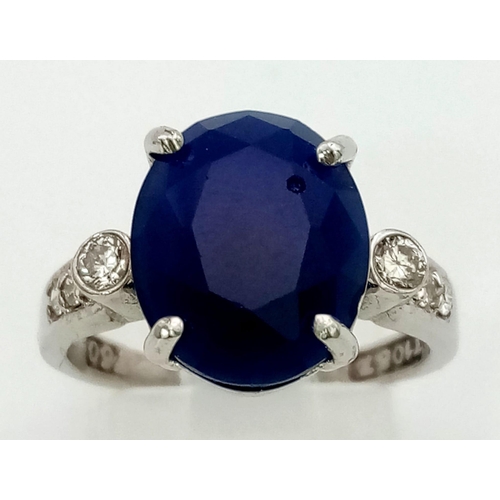 1311 - An 18K White Gold, Sapphire and Diamond Ring. Central oval sapphire with three round cut diamonds ei... 