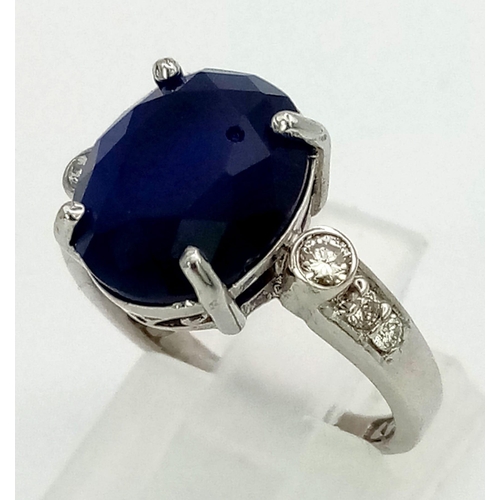 1311 - An 18K White Gold, Sapphire and Diamond Ring. Central oval sapphire with three round cut diamonds ei... 