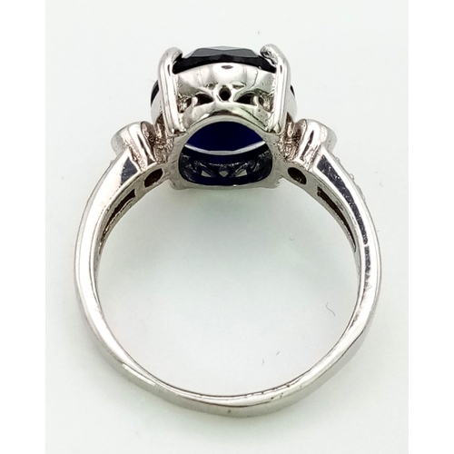 1311 - An 18K White Gold, Sapphire and Diamond Ring. Central oval sapphire with three round cut diamonds ei... 