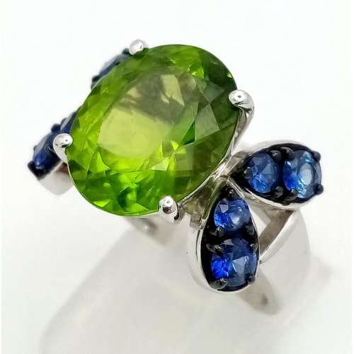 152 - A very attractive, platinum ring with a large, oval cut peridot, surrounded by eight, round cut tanz... 