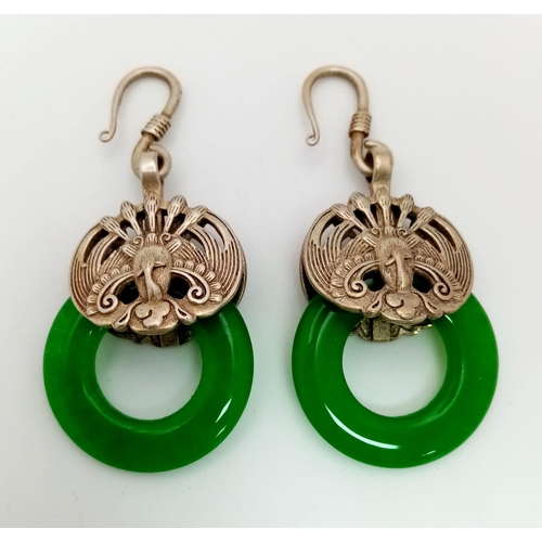 167 - An antique Chinese pair of silver earrings with green jade. Presented in a hand carved and pierced s... 