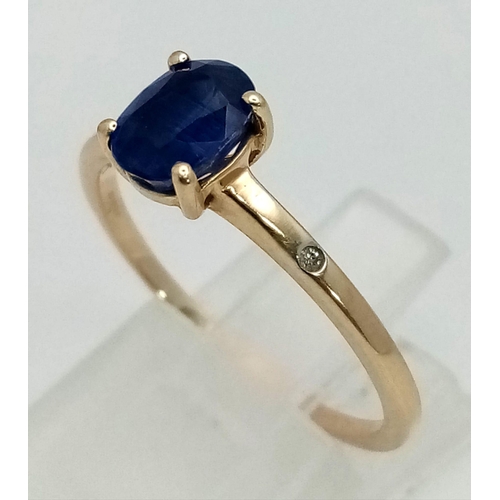 1497 - A 10K Yellow Gold Sapphire and Diamond Ring. Central oval sapphire with a small diamond either side.... 