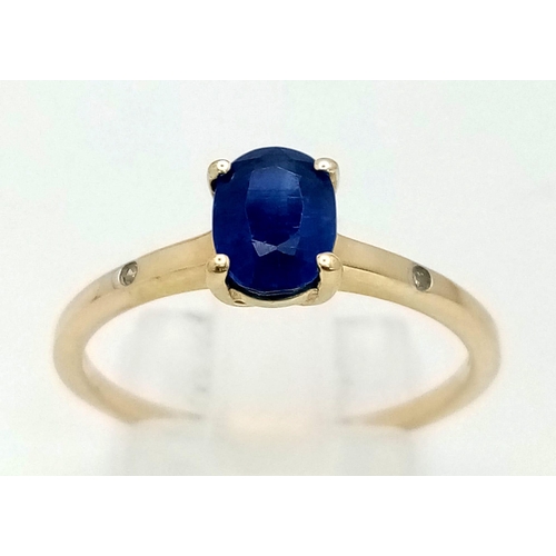 1497 - A 10K Yellow Gold Sapphire and Diamond Ring. Central oval sapphire with a small diamond either side.... 