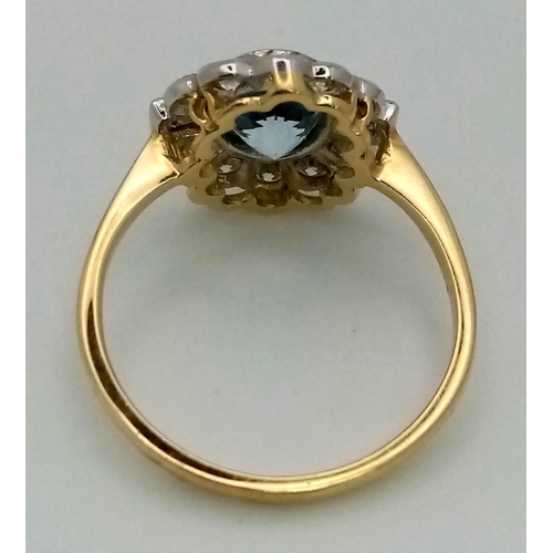 615 - A gorgeous 18K gold ring with a large, oval cut aquamarine, surrounded by a halo of round cut diamon... 