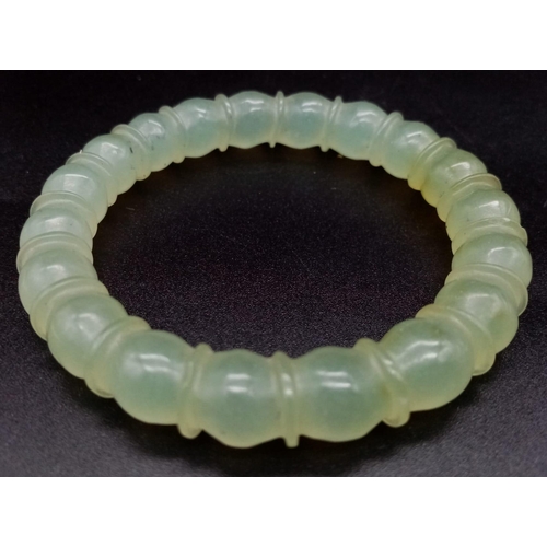 953 - An Antique Chinese Pale Celadon Jade Bangle. Ball-ridge design. 6cm inner diameter.