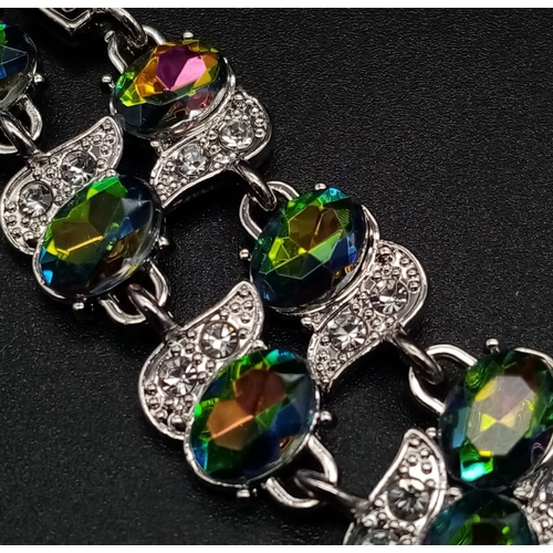 1276 - A Mystic Topaz Tennis Bracelet. Spare link attached. Set in white metal. 19cm