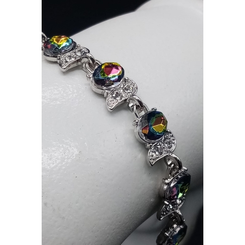 1276 - A Mystic Topaz Tennis Bracelet. Spare link attached. Set in white metal. 19cm