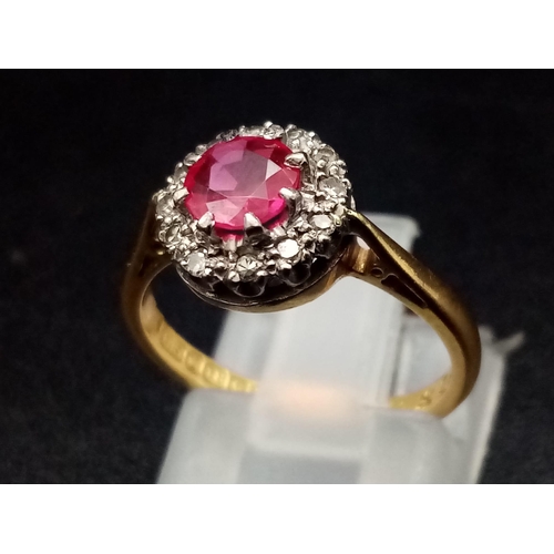 1261 - An 18K yellow gold ring with a round cut ruby surrounded by a halo of diamonds. Ring size: J1/2, wei... 