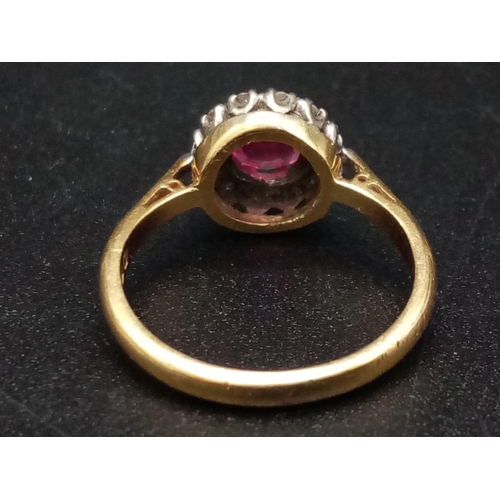 1261 - An 18K yellow gold ring with a round cut ruby surrounded by a halo of diamonds. Ring size: J1/2, wei... 