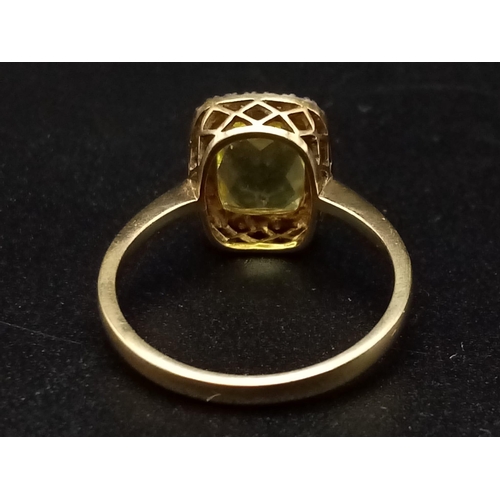 1265 - A 9K yellow gold ring with a large mix cut yellow beryl (app. 6 carats) surrounded by a halo of diam... 