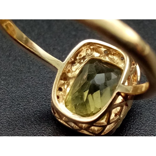 1265 - A 9K yellow gold ring with a large mix cut yellow beryl (app. 6 carats) surrounded by a halo of diam... 