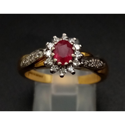 1269 - An 18K yellow gold ring with an oval cut ruby surrounded by a halo of diamonds with further diamonds... 