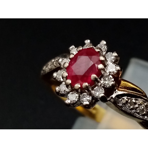 1269 - An 18K yellow gold ring with an oval cut ruby surrounded by a halo of diamonds with further diamonds... 