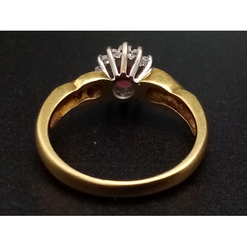 1269 - An 18K yellow gold ring with an oval cut ruby surrounded by a halo of diamonds with further diamonds... 