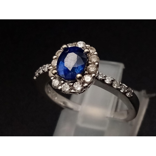 1277 - An 18K white gold ring with a beautiful, natural, oval cut, blue sapphire, surrounded by a halo of d... 