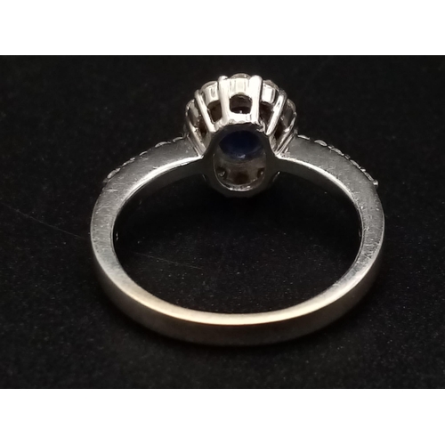 1277 - An 18K white gold ring with a beautiful, natural, oval cut, blue sapphire, surrounded by a halo of d... 