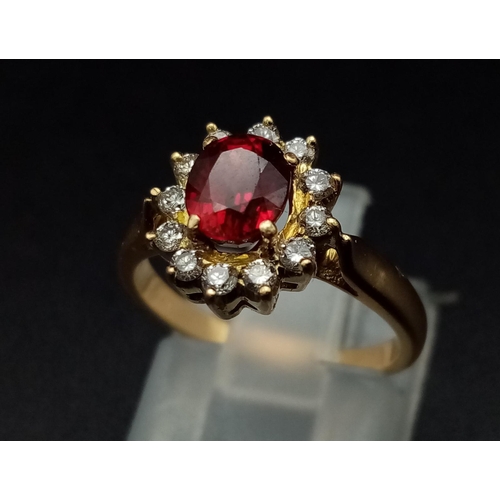 1281 - An 18K yellow gold ring with an oval cut ruby surrounded by a halo of diamonds.  Ring size: I, weigh... 