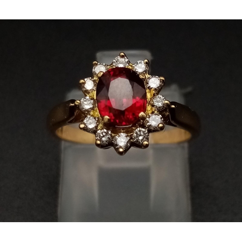 1281 - An 18K yellow gold ring with an oval cut ruby surrounded by a halo of diamonds.  Ring size: I, weigh... 