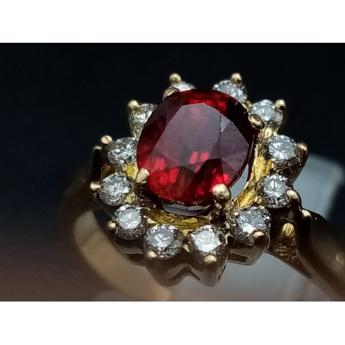 1281 - An 18K yellow gold ring with an oval cut ruby surrounded by a halo of diamonds.  Ring size: I, weigh... 