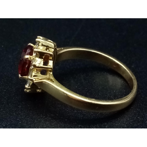 1281 - An 18K yellow gold ring with an oval cut ruby surrounded by a halo of diamonds.  Ring size: I, weigh... 