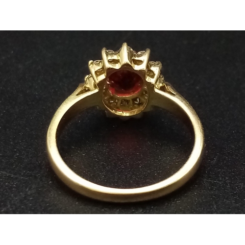 1281 - An 18K yellow gold ring with an oval cut ruby surrounded by a halo of diamonds.  Ring size: I, weigh... 