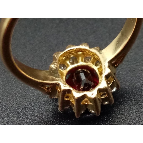 1281 - An 18K yellow gold ring with an oval cut ruby surrounded by a halo of diamonds.  Ring size: I, weigh... 