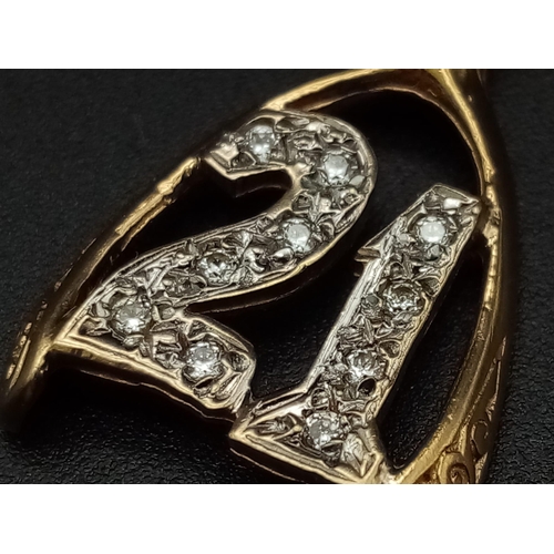 549 - A 9K yellow gold pendant/charm in the shape of a wishbone with the number 21 covered with cubic zirc... 