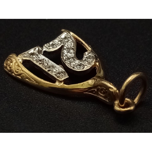 549 - A 9K yellow gold pendant/charm in the shape of a wishbone with the number 21 covered with cubic zirc... 