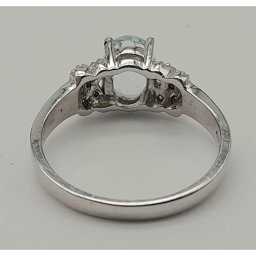 1599 - A 9K WHITE GOLD RING WITH COLOURED OVAL CENTRE STONE AND ORNATE SHOULDERS.2.9gms   size N.