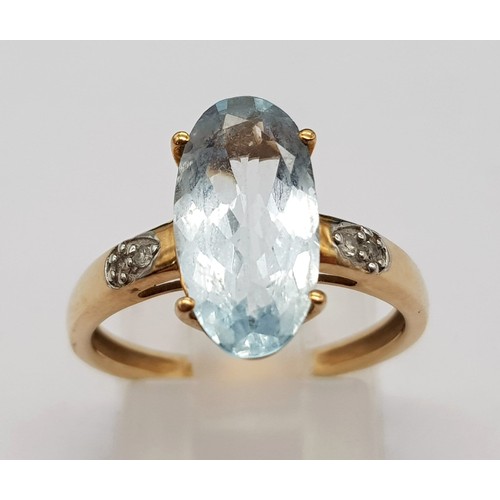 1036 - A 9K Yellow Gold Blue Gemstone and Diamond Ring. Elongated central oval stone with two small diamond... 