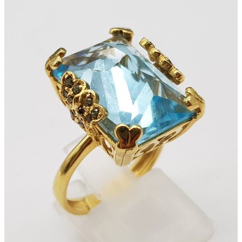 359 - An 18K Yellow Gold Blue Topaz Ring. Pale blue 10ct stone in a scroll setting. 8.81g total weight. Si... 