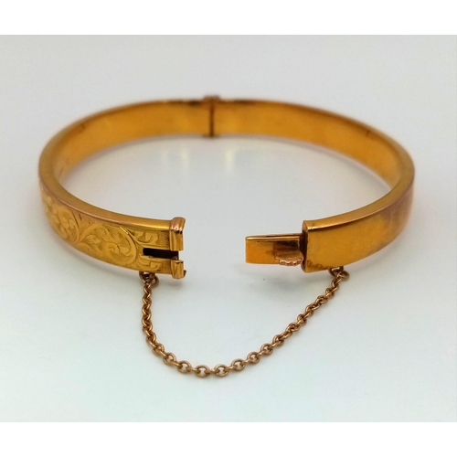 11 - A Vintage 9K Yellow Gold Bangle. Clip opening with safety chain. Scrolled decoration. 6cm inner diam... 