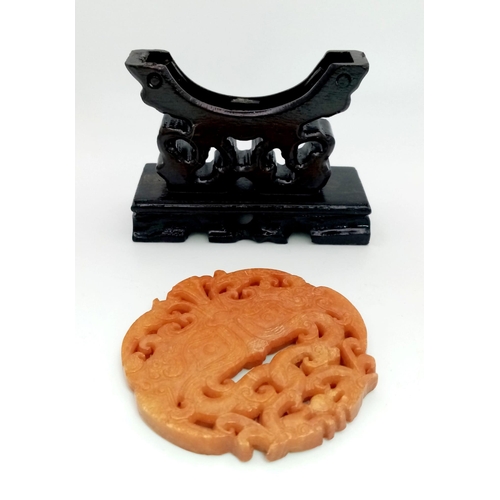 273 - An antique, Chinese, hand carved orange jade amulet on a custom made wooden carved base. The amulet ... 