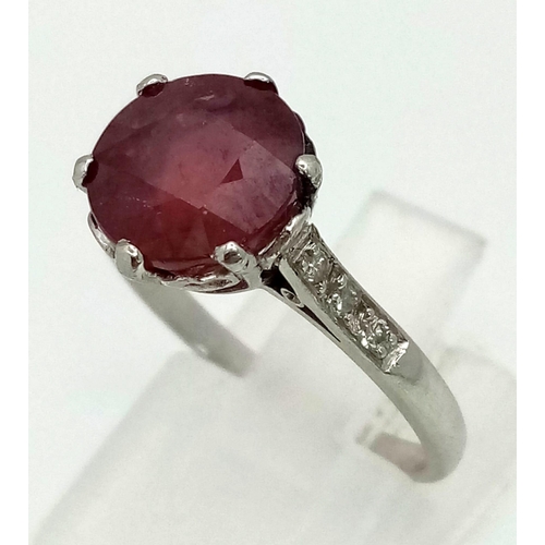 158 - An 18K White Gold, Ruby and Diamond Ring. A 3.3ct round ruby with six brilliant round cut diamonds o... 