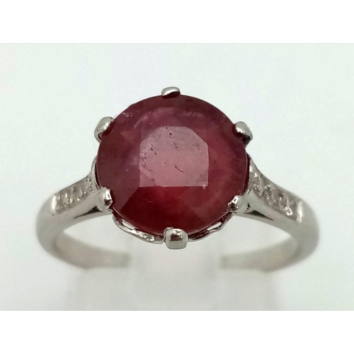 158 - An 18K White Gold, Ruby and Diamond Ring. A 3.3ct round ruby with six brilliant round cut diamonds o... 