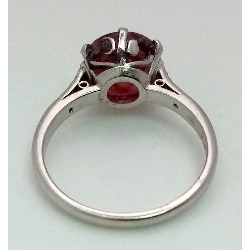 158 - An 18K White Gold, Ruby and Diamond Ring. A 3.3ct round ruby with six brilliant round cut diamonds o... 