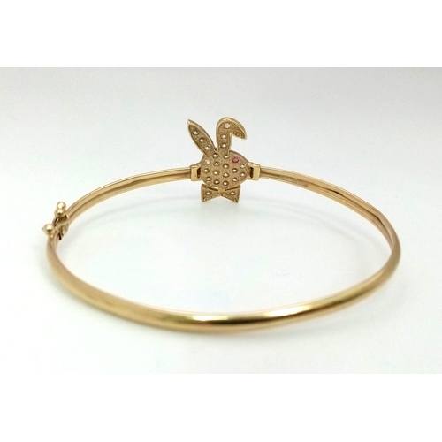 1006 - A 9K yellow gold, stone set, Playboy bunny bangle with safety catch. Weight: 4.5 g.