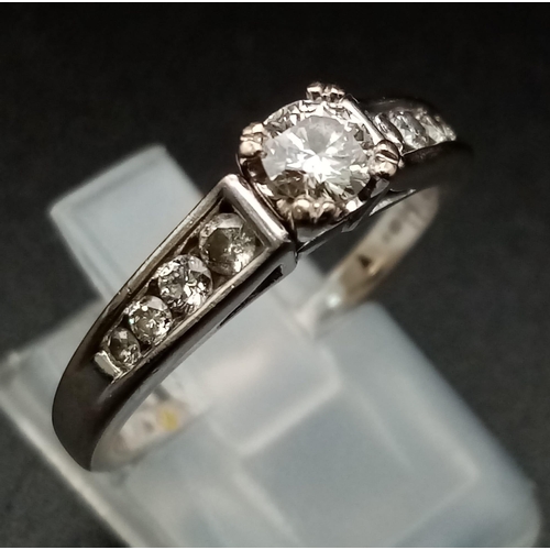 164 - An 18K White Gold Diamond Ring. Central brilliant round cut diamond with a further four diamonds on ... 