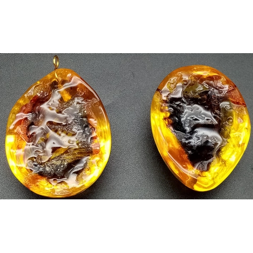 238 - Two large resin amber pendants with a butterfly inclusion. App 6 cm long.