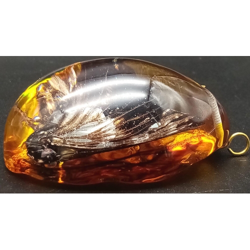 238 - Two large resin amber pendants with a butterfly inclusion. App 6 cm long.